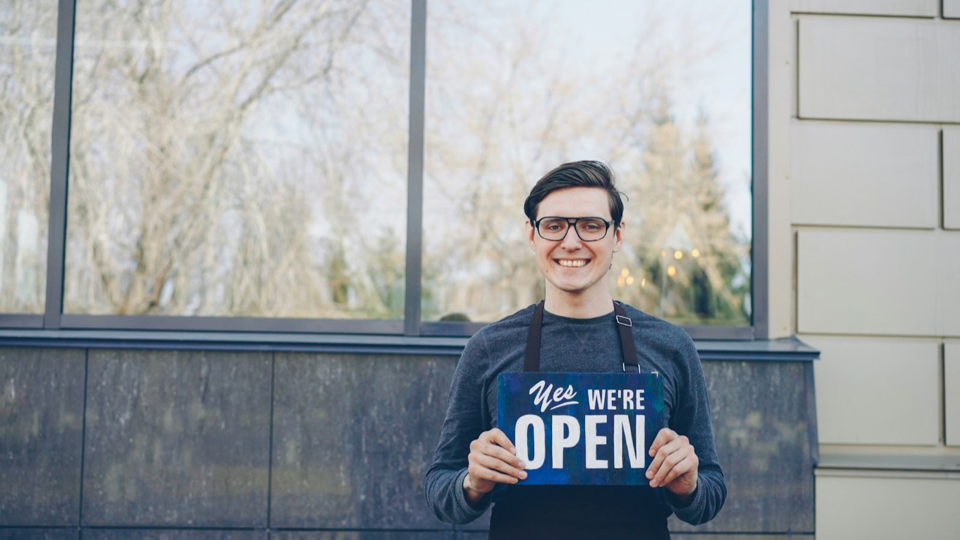 Unternehmer hält ein Schild mit der Aufschrift „We’re open“